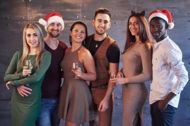 Yeni yıl geliyor! Partide Noel Baba şapkası takmış neşeli, çoklu etnik kökenli bir grup genç insan duygusal yaşam tarzı insanları konseptine poz veriyor..
