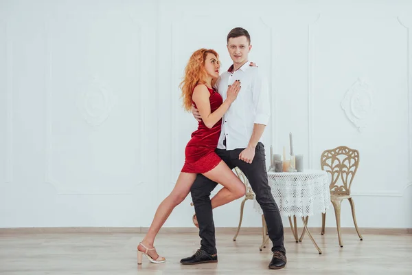 スタジオの白い背景に隔離された赤いドレスと男踊りの若い美しい女性 — ストック写真