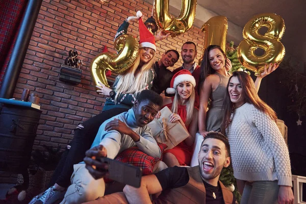 Grupo de amigos alegres faz selfie. O novo ano de 2018 está chegando. Comemore o ano novo em uma atmosfera caseira acolhedora — Fotografia de Stock