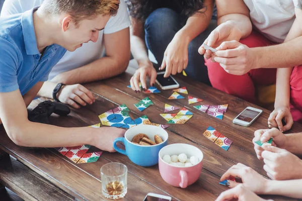 Top view creative photo of friends sitting at wooden table. Friends having fun while playing board game