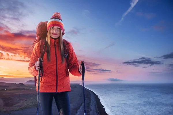 A woman with a backpack rest on top of the mountain and enjoy the views of the valley.