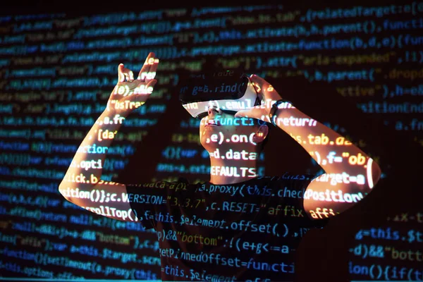 Double exposure of a caucasian man and Virtual reality VR headset is presumably a gamer or a hacker cracking the code into a secure network or server, with lines of code