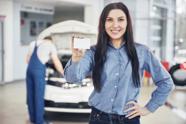 Vacker Kvinna Har Ett Visitkort Från Bilservicecentret Mekanikern Inspekterar Bilen — Stockfoto