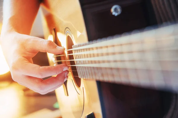 Guitarist plays guitar on wooden background, close up.