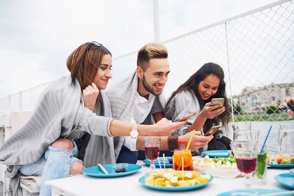 Mutlu genç arkadaşlar bir masada oturup dışarıda piknik yapıyorlardı..