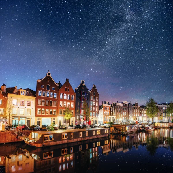 在阿姆斯特丹的美丽夜晚 夜景照明的建筑物和船附近运河里的水 — 图库照片