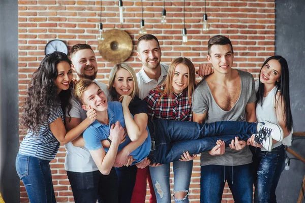 Group portrait of multi-ethnic boys and girls with colorful fashionable clothes holding friend and posing on a brick wall, Urban style people having fun, Concepts about youth and togetherness lifestyle.