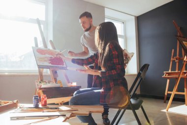 Sanatçılar stüdyoda resim çizerler. Yaratıcı sanatçılar, stüdyoda yağlı boya ile tuvale boyanmış renkli bir tablo tasarladılar..