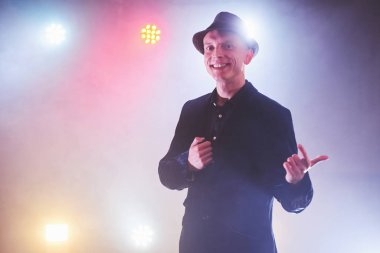 Stüdyoda mavi ışıklı, resmi kıyafetli yakışıklı bir adam var..