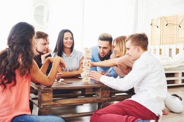 Bir grup yaratıcı arkadaş ahşap masada oturuyor. İnsanlar masa oyunu oynarken eğleniyor.