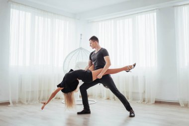 Genç çift dans latin müzik: Bachata, merengue, salsa. Beyaz Oda üzerinde iki zerafet poz.
