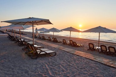 Kumsaldaki kumlu sahilin manzarası. Deniz ve dağlara karşı güneş yatakları ve şemsiyeler açık. Otelde. Tatil köyü. Tekirova-Kemer. Türkiye