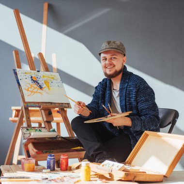 Sanatçı adam bitirme tarafından tasarlanmış eserini bir fırça elinde tutan