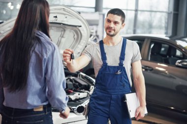 Mekanik kadın istemci araba anahtarları veren görünümü kırpılmış.