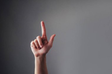 İnsan elinin yakın görüntüsü, gri arka planda işaret parmağına dokunuyor. Vale dokunmatik ekranı. Bir şeyi işaret ediyor.