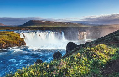 Gün batımında Godafoss şelalesi. Muhteşem bir manzara. Güzel kümülüs bulutları. İzlanda