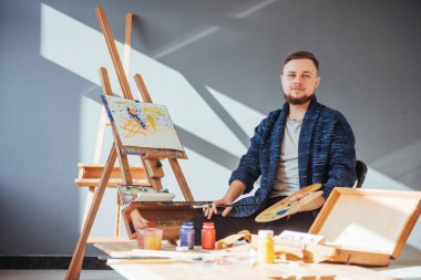 Sanatçı adam bitirme tarafından tasarlanmış eserini bir fırça elinde tutan