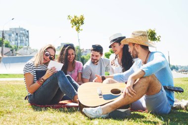 Mutlu genç arkadaşlarım parkta piknik. Onlar tüm mutlu, eğleniyor, gülümseyen ve gitar çalmak vardır.