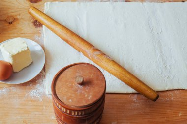 ahşap bir oklava ile unlu çalışma yüzeyinin taze yapılmış pasta bloğunu silindir dışarı.