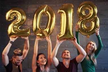 Bir grup neşeli genç, yeni bir 2018 yılının geldiğini belirten rakamlar tutuyor. Parti, yeni yılın kutlanmasına adanmıştır. Gençlik birlikteliği yaşam tarzı kavramları.