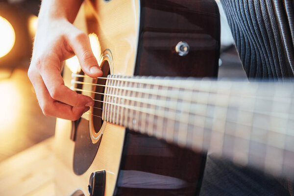 Guitarist plays guitar on wooden background, close up.
