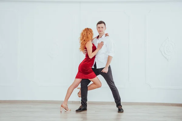 穿着红衣服的年轻漂亮的女人和一个跳舞的男人 在演播室的白色背景上孤身一人 — 图库照片