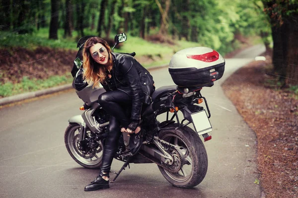 一个穿着皮衣 性感迷人的女孩站在外面的一辆摩托车旁边 — 图库照片