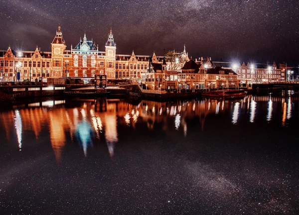 阿姆斯特丹美丽的夜晚 运河中靠近水面的建筑物和船只夜间照明 明亮的夜空 星云和星系 深空星图 — 图库照片