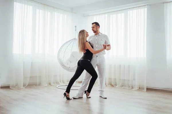 年轻夫妇跳舞拉丁音乐 Bachata 梅伦格 萨尔萨舞 白色房间的两个优雅姿势 — 图库照片