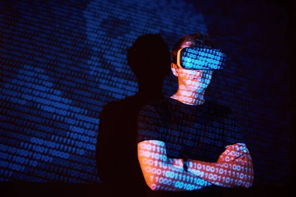 Double exposure of a caucasian man and Virtual reality VR headset is presumably a gamer or a hacker cracking the code into a secure network or server, with lines of code
