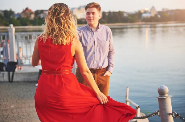 背景に湖と夏の赤いドレスと若い男のダンスで幸せな美しい女性 赤と白のコントラスト — ストック写真