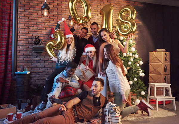 Photo with friends. Group of cheerful young people make a festive photo near the Christmas tree. Happy New 2018 Year to you! Concept of entertainment and lifestyle