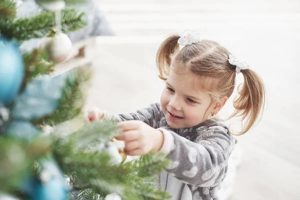 メリークリスマスとハッピーホリデー 若いです女の子助けて飾るクリスマスツリー いくつかのクリスマスの赤ちゃんを保持彼女の手 — ストック写真