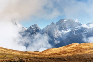 Sonbahar manzara ve kar dağlarda güzel cumulus bulutları. Ana Kafkas Ridge. Türü Mount dır Mheyer, Gürcistan.