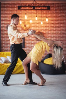 Dans eden genç çift Latin müziği Bachata, merengue, salsa. Kafede iki zarif poz, tuğla duvarlı..