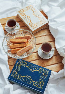 Tahta bir arka planda izole edilmiş çay, kurabiye ve kitaplar.
