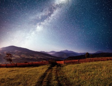 Dağ yaz manzarası. Yüksek otlar ve parlak gece gökyüzü yıldızlar, nebula ve galaksiyle. Derin gökyüzü gökyüzü fotoğrafı.