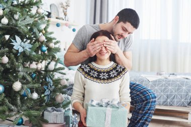 Genç çift Noel 'i kutluyor. Bir adam aniden karısına bir hediye sundu. Aile mutluluğu ve refah kavramı..