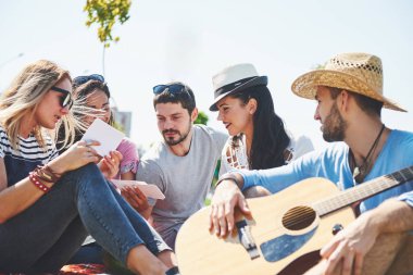 Mutlu genç arkadaşlarım parkta piknik. Onlar tüm mutlu, eğleniyor, gülümseyen ve gitar çalmak vardır.