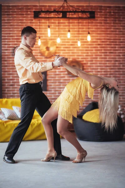 Young couple dancing latin music: Bachata, merengue, salsa. Two elegance pose on cafe with brick walls.
