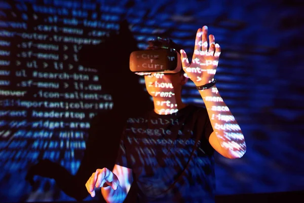 Double exposure of a caucasian man and Virtual reality VR headset is presumably a gamer or a hacker cracking the code into a secure network or server, with lines of code