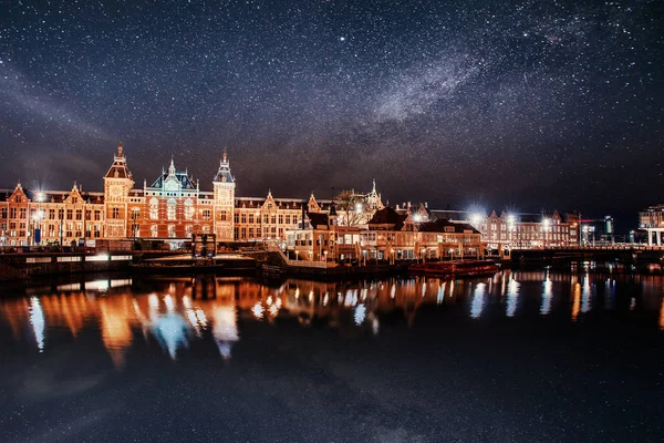 阿姆斯特丹美丽的夜晚 运河中靠近水面的建筑物和船只夜间照明 明亮的夜空 星云和星系 深空星图 — 图库照片