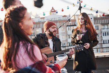 Ruhun nasıl şarkı söylediğini hisset. Genç arkadaşlar çatıda alkol ve gitarla parti veriyorlar..