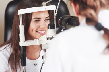 Gözler mükemmel durumda. Optometrist genç ve güzel bir kadının görüşünü kontrol ediyor..