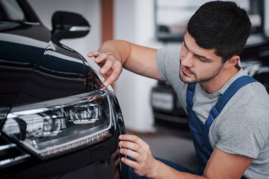 Kulübede yeni bir araba seçen mutlu bir adamın portresi.