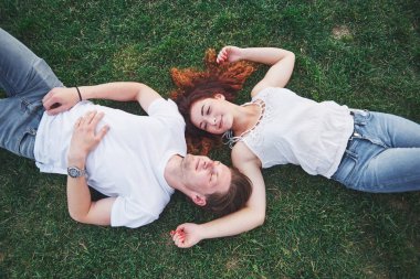 Parktaki çimlerin üzerinde yatan romantik iki genç insan. Mutlu görünüyorlar. Yukarıdan görüntüle