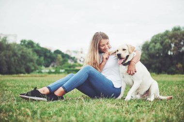 Çekici genç kadın labrador açık havada. Kadın ile köpek labrador geri almak yeşil çimenlerin üzerinde.