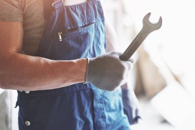 Bir işçi kostüm fabrikasının arka planında metal anahtarı olan eldivenleri teslim et.