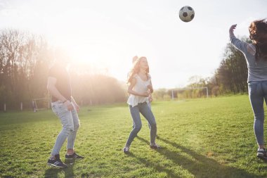 Gündelik kıyafetli bir grup arkadaş açık havada futbol oynuyor. İnsanlar eğleniyor ve eğleniyor. Aktif dinlenme ve manzaralı gün batımı.