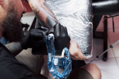 Dövme makinesini kapat. Siyah steril eldivenler ustası. Kuaförde resim yapıyor..